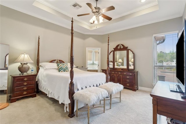 carpeted bedroom featuring crown molding, connected bathroom, a tray ceiling, and ceiling fan