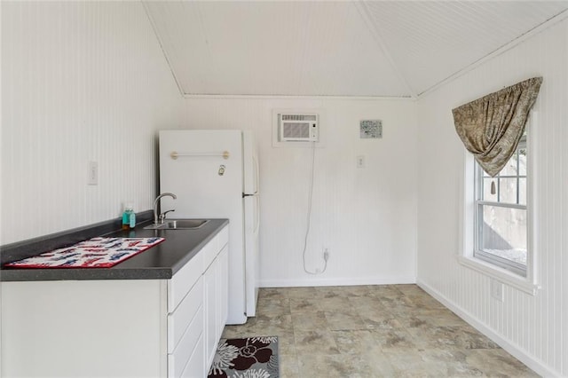 kitchen featuring an AC wall unit, white cabinetry, lofted ceiling, sink, and white refrigerator