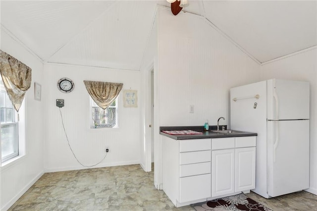 kitchen featuring lofted ceiling, a sink, dark countertops, and freestanding refrigerator