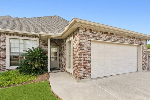 property entrance with driveway, a shingled roof, and brick siding