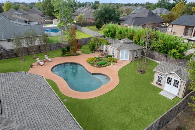 view of pool featuring an outbuilding, a patio area, and a lawn