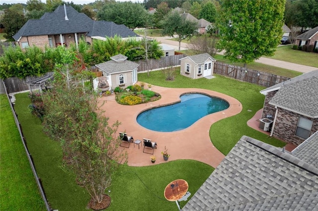 view of swimming pool with a yard, a patio area, and a storage shed