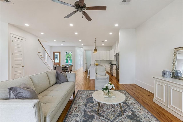 living room with ceiling fan, sink, and light hardwood / wood-style floors