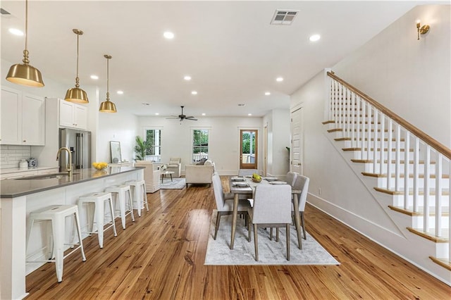 dining space with ceiling fan, sink, and light wood-type flooring