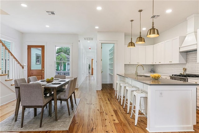 kitchen featuring pendant lighting, sink, decorative backsplash, and white cabinets