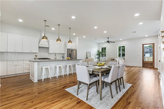 dining space featuring ceiling fan, sink, and light wood-type flooring