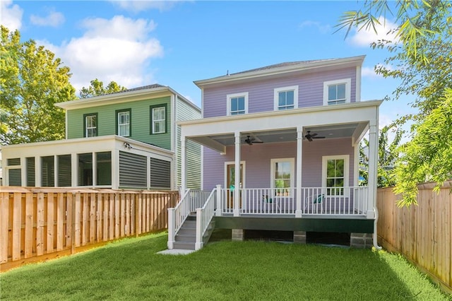 back of property with a wooden deck, ceiling fan, and a yard