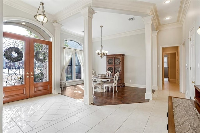 tiled entryway with an inviting chandelier, ornamental molding, decorative columns, and french doors