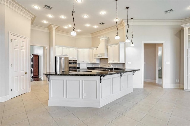 kitchen with premium range hood, pendant lighting, dark stone countertops, white cabinets, and stainless steel appliances