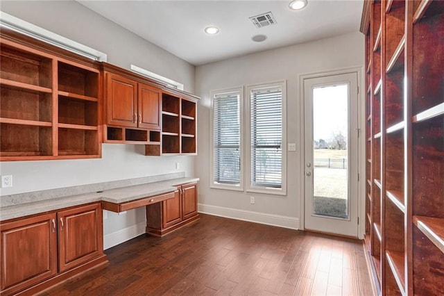 unfurnished office featuring built in desk and dark hardwood / wood-style floors