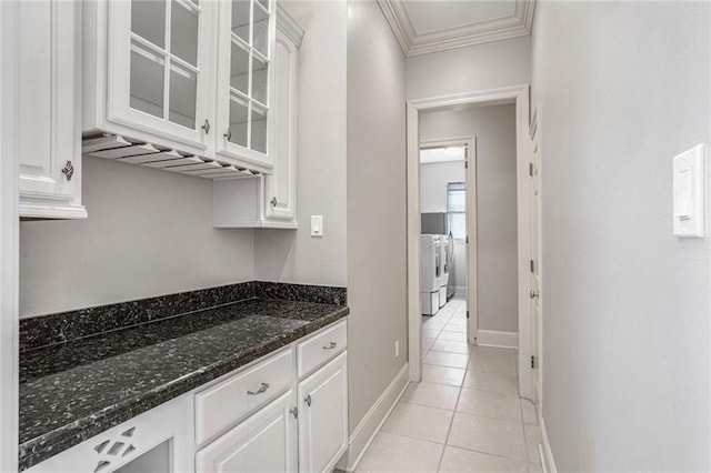 bar featuring washing machine and dryer, dark stone countertops, and white cabinets