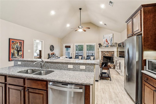 kitchen with appliances with stainless steel finishes, light hardwood / wood-style floors, sink, and light stone countertops