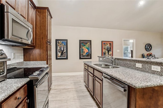 kitchen featuring light stone counters, sink, decorative backsplash, and stainless steel appliances