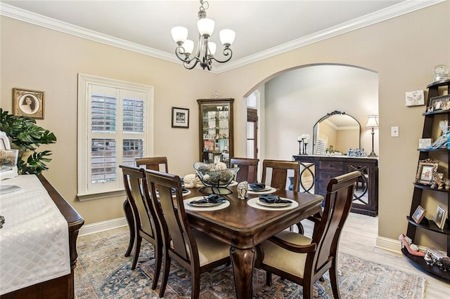 dining space featuring an inviting chandelier, ornamental molding, and light hardwood / wood-style floors