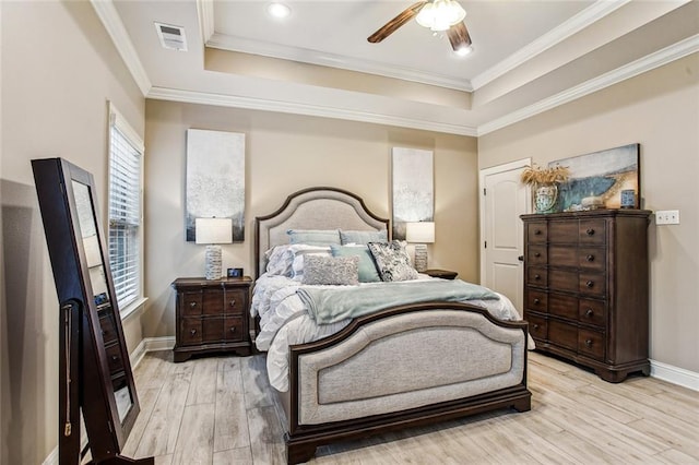 bedroom featuring crown molding, ceiling fan, a raised ceiling, and light hardwood / wood-style flooring