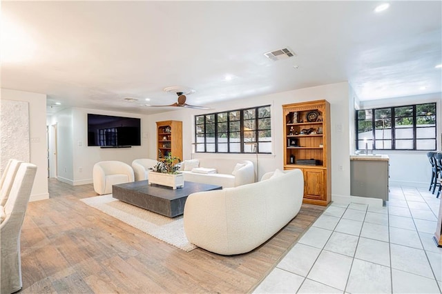 living room featuring ceiling fan, sink, light hardwood / wood-style flooring, and a wealth of natural light