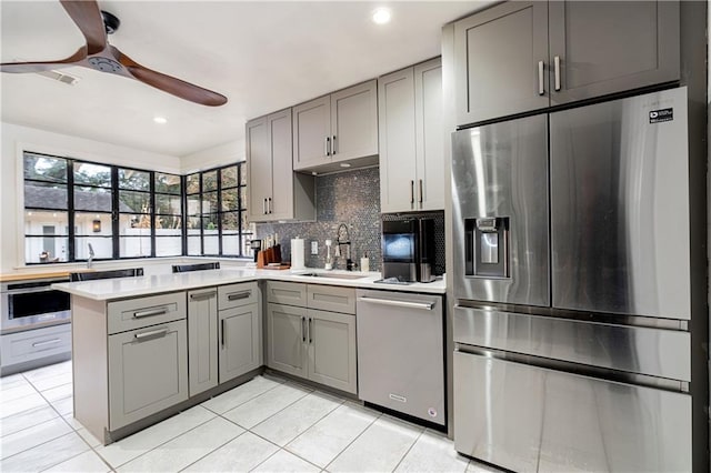 kitchen featuring stainless steel appliances, sink, gray cabinets, and kitchen peninsula