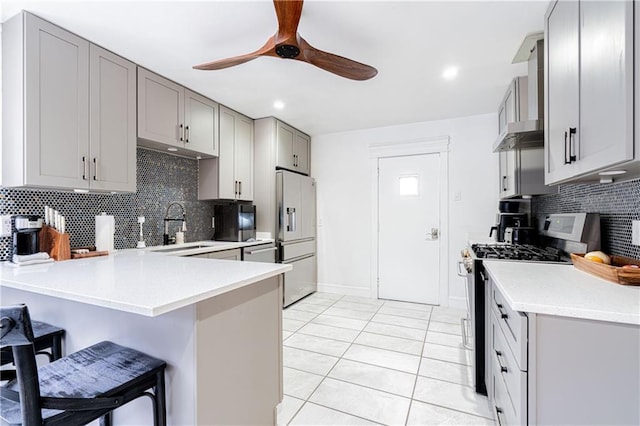 kitchen with appliances with stainless steel finishes, sink, a kitchen breakfast bar, ceiling fan, and kitchen peninsula