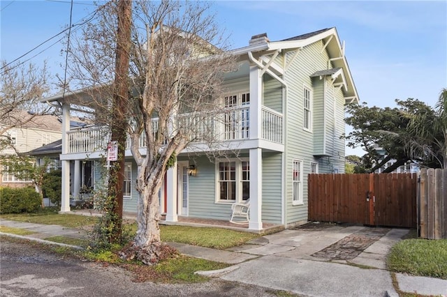 5817 Magnolia St, New Orleans, LA 70115 - view of property with a balcony, fence, a chimney, and covered porch