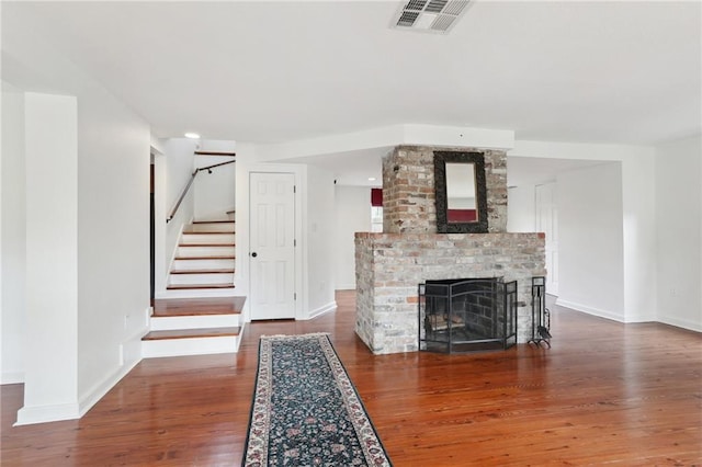 unfurnished living room with a brick fireplace and dark hardwood / wood-style floors