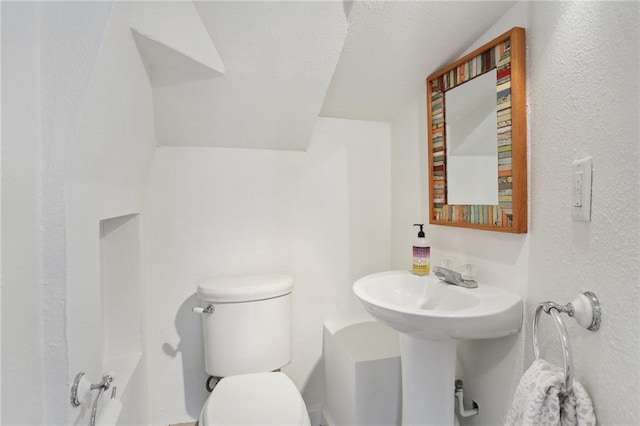 bathroom with lofted ceiling, a textured ceiling, and toilet