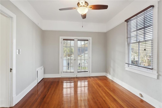 empty room with dark hardwood / wood-style flooring, a tray ceiling, and ceiling fan