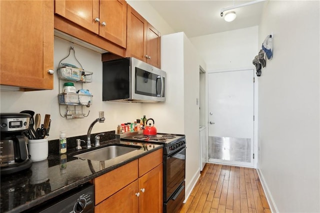 kitchen featuring dark stone counters, sink, light hardwood / wood-style flooring, and black appliances