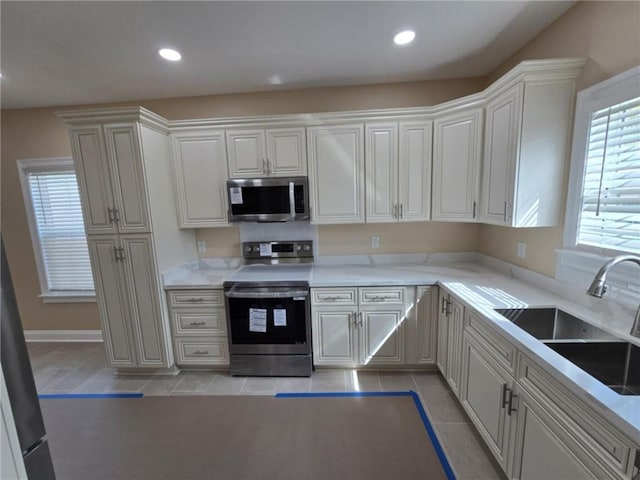 kitchen featuring light tile patterned floors, stainless steel appliances, sink, and a wealth of natural light