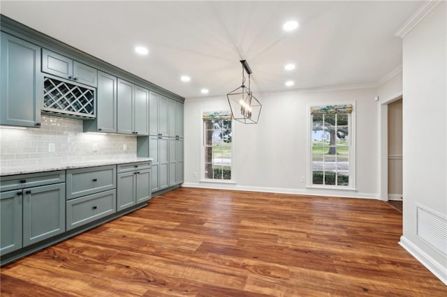 kitchen with dark hardwood / wood-style floors, tasteful backsplash, hanging light fixtures, ornamental molding, and a notable chandelier