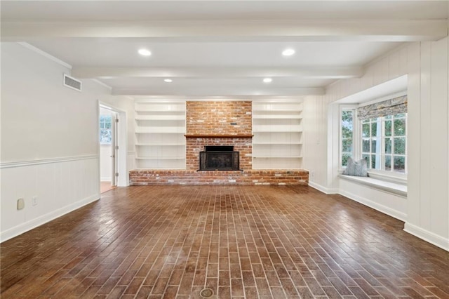 unfurnished living room with built in shelves, a brick fireplace, and beamed ceiling