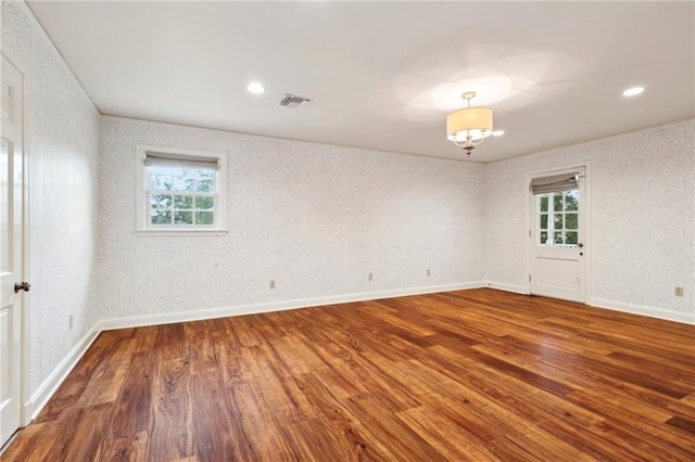 unfurnished room featuring an inviting chandelier and hardwood / wood-style floors