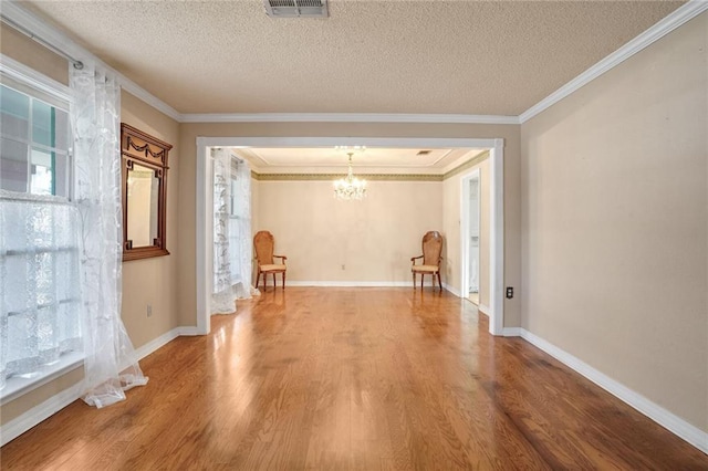 interior space with an inviting chandelier, wood-type flooring, crown molding, and a textured ceiling