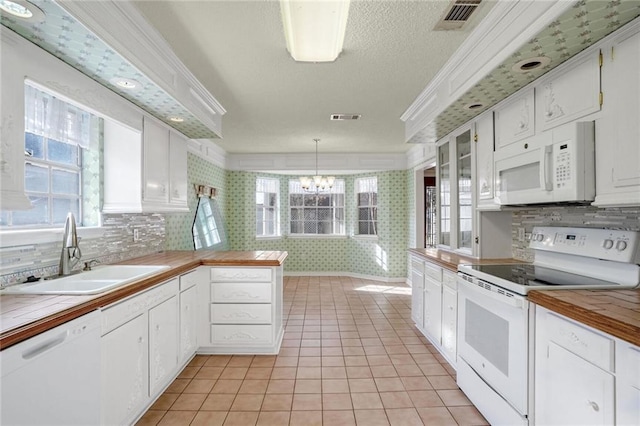 kitchen featuring pendant lighting, white appliances, sink, and white cabinets