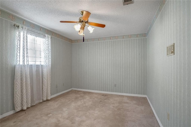 empty room featuring ceiling fan, carpet floors, and a textured ceiling