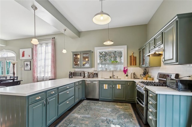 kitchen with pendant lighting, sink, appliances with stainless steel finishes, decorative backsplash, and kitchen peninsula