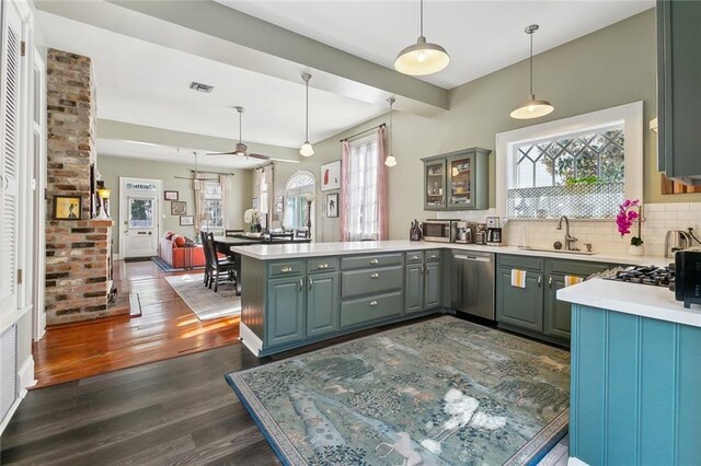 kitchen with sink, dark hardwood / wood-style floors, tasteful backsplash, stainless steel dishwasher, and kitchen peninsula