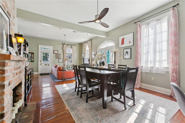 dining room with ceiling fan, wood-type flooring, and a fireplace