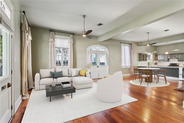 living room with visible vents, ceiling fan, and wood finished floors