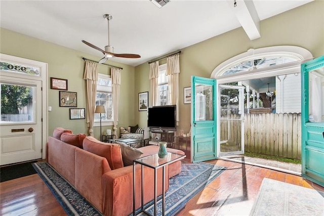 living room with beamed ceiling, a ceiling fan, hardwood / wood-style flooring, and visible vents
