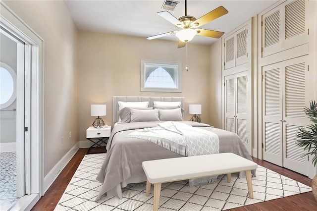 bedroom with visible vents, baseboards, multiple closets, and wood finished floors