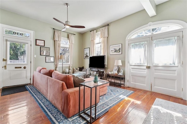 living room with beam ceiling, wood-type flooring, and ceiling fan