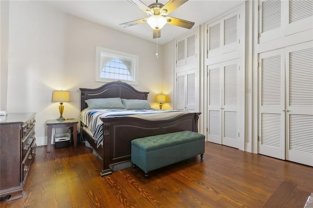 bedroom featuring dark wood-type flooring, two closets, and ceiling fan