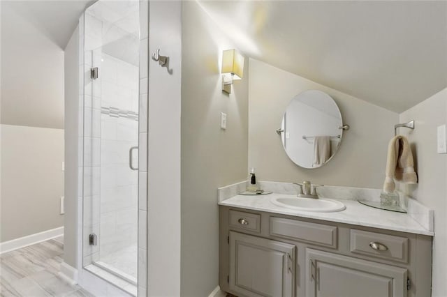 bathroom featuring vanity, a shower with shower door, and vaulted ceiling