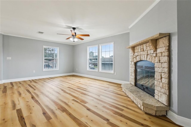 unfurnished living room with crown molding, a wealth of natural light, a fireplace, and light hardwood / wood-style floors