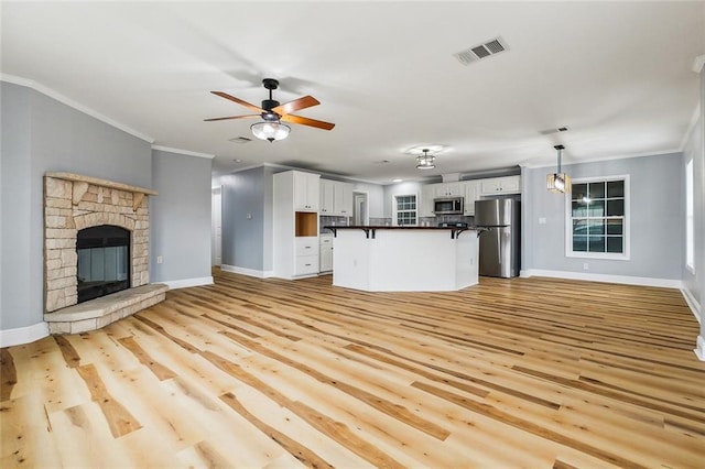 unfurnished living room featuring crown molding, light wood-type flooring, ceiling fan, and a fireplace