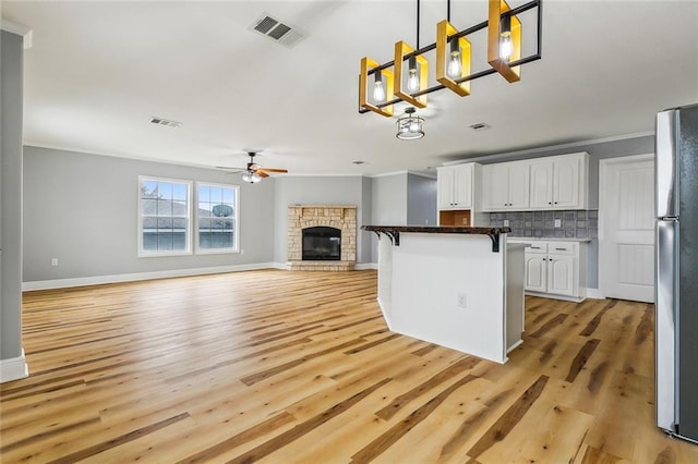 kitchen with a kitchen bar, white cabinetry, tasteful backsplash, decorative light fixtures, and stainless steel fridge