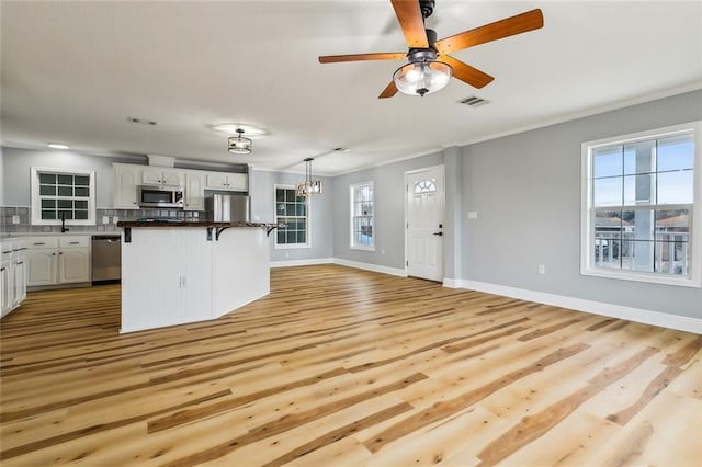 kitchen with hanging light fixtures, stainless steel appliances, a breakfast bar, and white cabinets