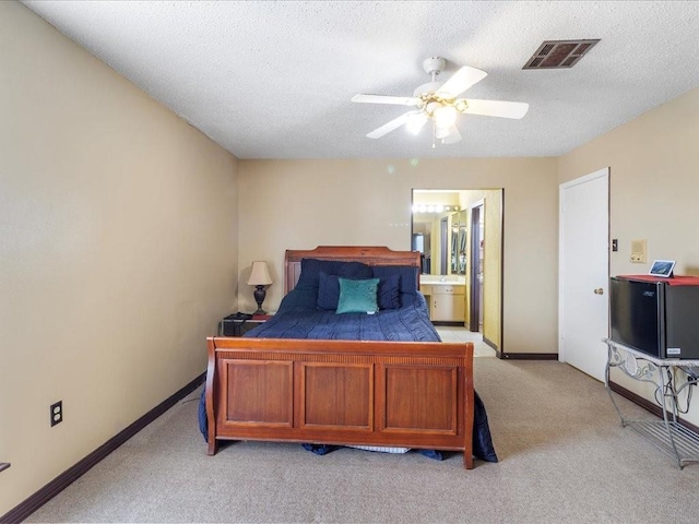 bedroom featuring ceiling fan, connected bathroom, light carpet, and a textured ceiling