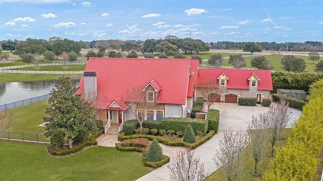 view of front of property featuring a garage, a water view, and a front lawn