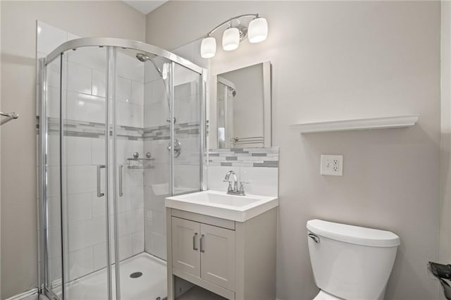 bathroom featuring vanity, tasteful backsplash, toilet, and walk in shower